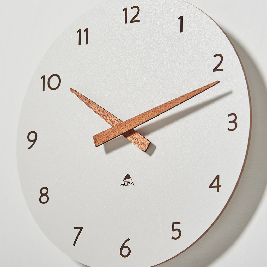 White wall clock with wooden hands on a light grey background