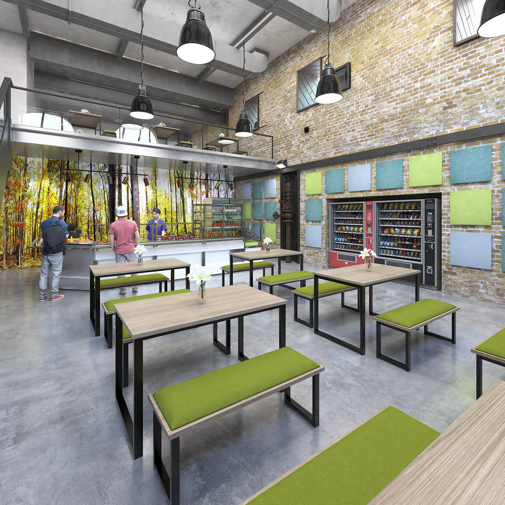 Industrial-style office canteen with long wooden tables and green bench seating, brick walls with acoustic panels, vending machines, and a serving counter under pendant lighting.