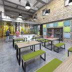 Industrial-style office canteen with long wooden tables and green bench seating, brick walls with acoustic panels, vending machines, and a serving counter under pendant lighting.