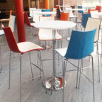 Colourful bar stools around a round poseur table in a modern setting