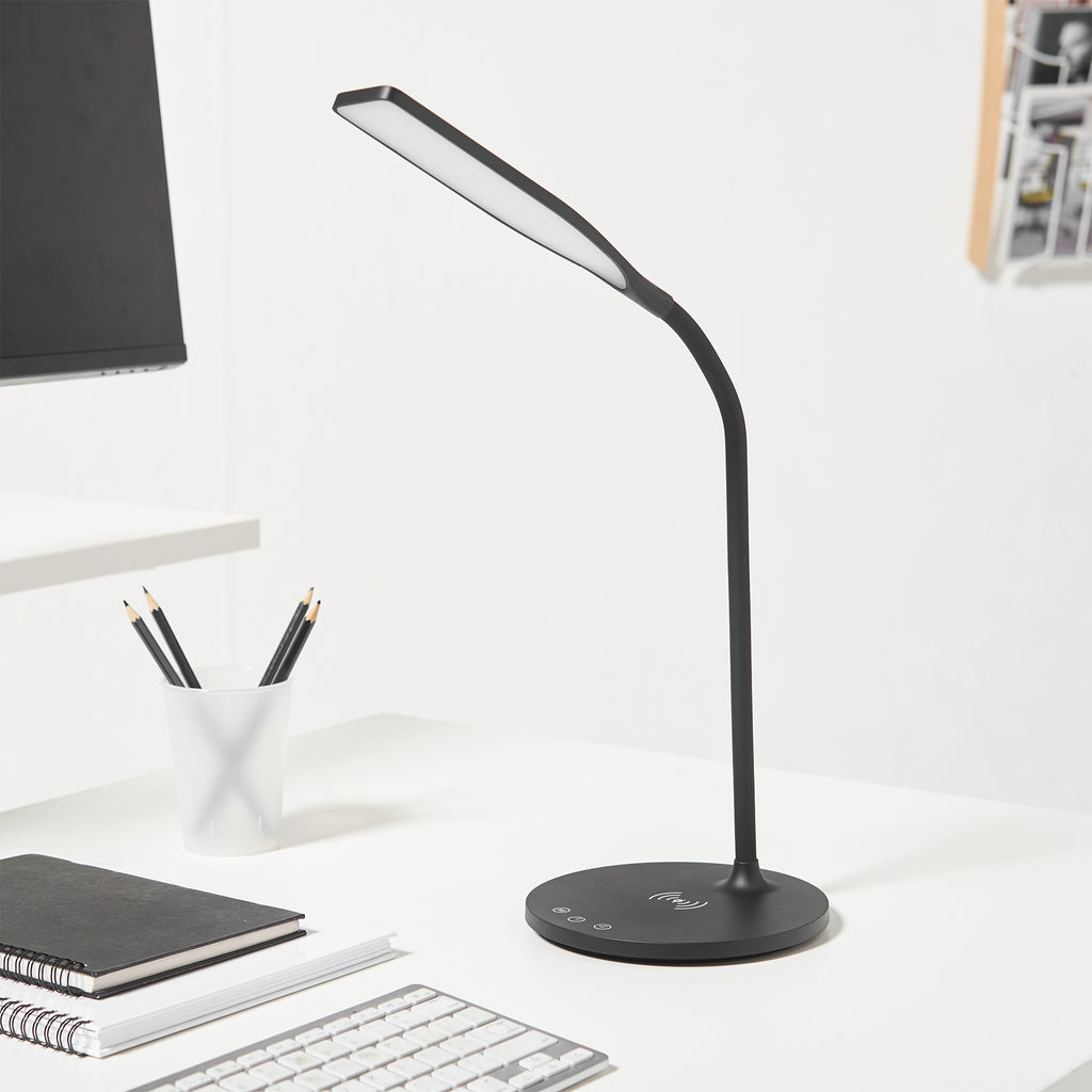 Black LED desk lamp on a white desk with stationery items
