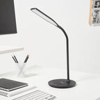 Black LED desk lamp on a white desk with stationery items