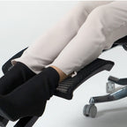 Person using a footrest on an office chair with a plain background