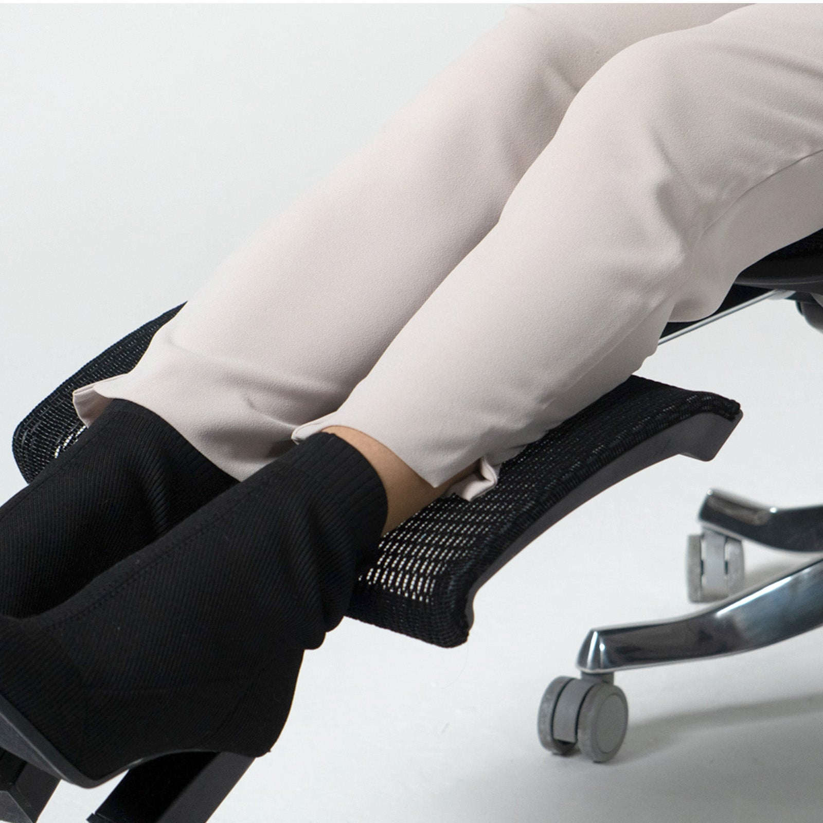 Person using a footrest on an office chair with a plain background