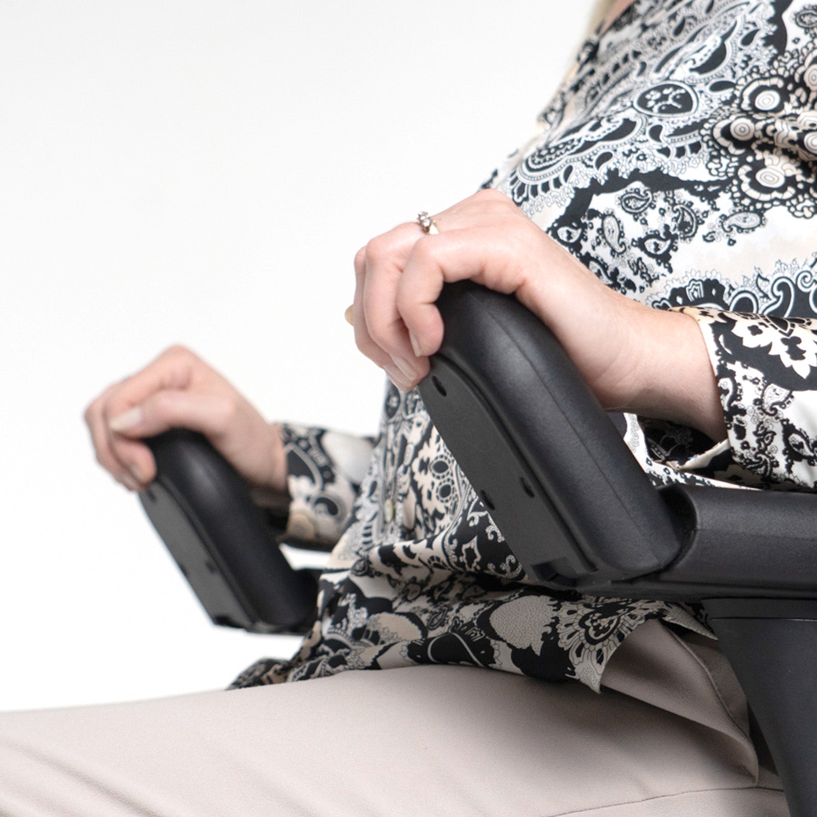 Person using a chair armrest adjustment on a white background
