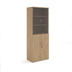Tall office storage cupboard with a wood-effect carcass, lockable lower doors, and upper glass display doors with internal shelving, shown on a white background.
