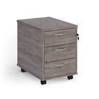 Grey wooden file cabinet with three drawers on wheels against a white background
