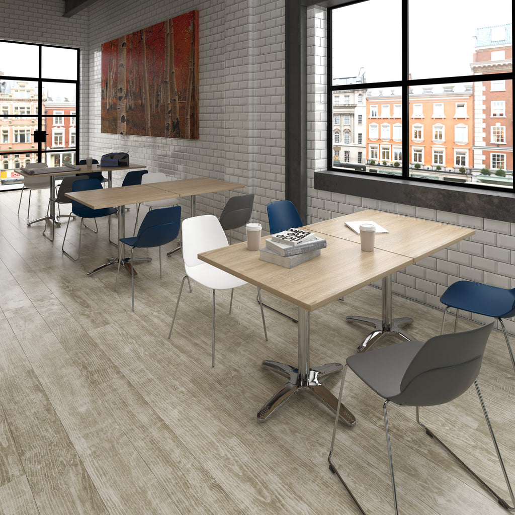 Modern office space with wooden tables and chairs near large windows.