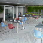 Modern office breakout area with café-style tables, colourful chairs, acoustic meeting pods, and green wall features for relaxed collaboration.