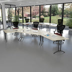 Flexible training room with curved tables, ergonomic office chairs, and large windows overlooking greenery, designed for collaborative learning.