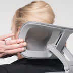 Close-up of a mesh ergonomic office chair headrest being adjusted by hand, demonstrating personalised neck and head support.