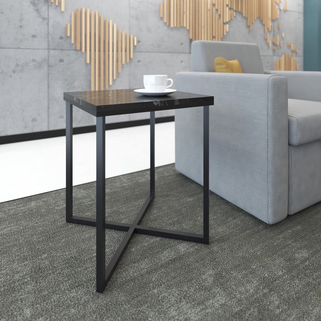 Small modern side table with black metal frame and dark top beside a lounge chair, styled with a coffee cup in a reception area.