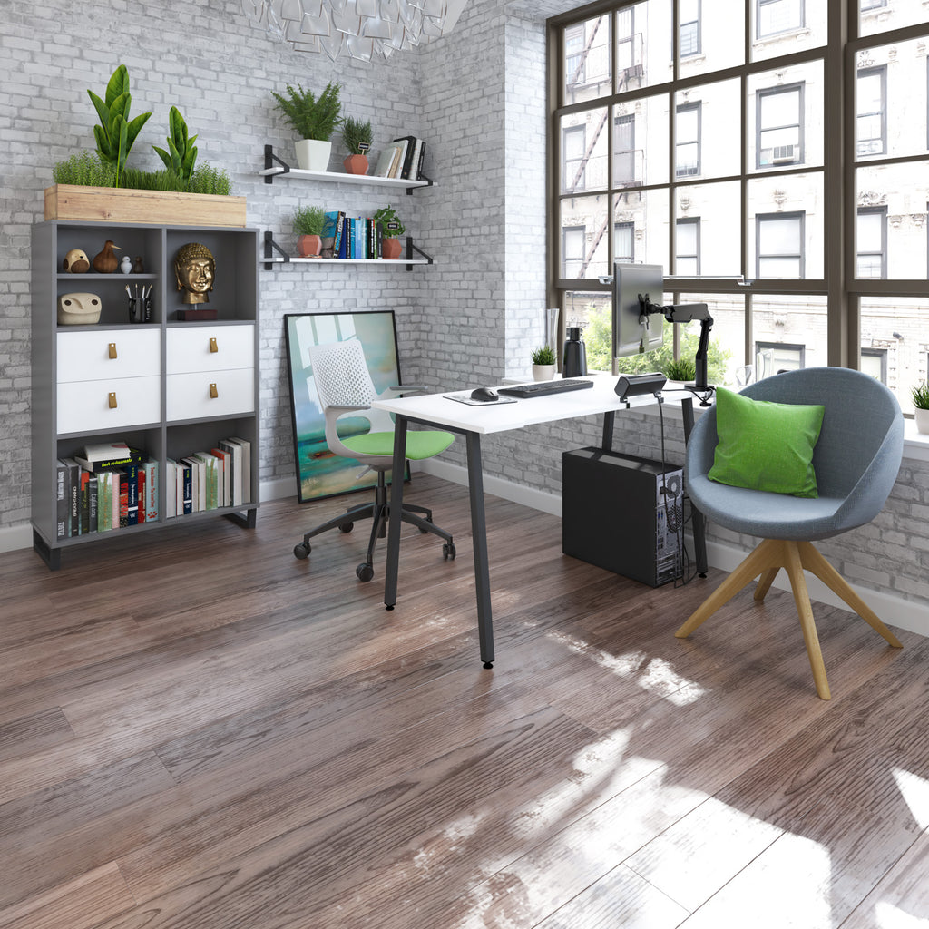 Stylish home office with white desk, storage unit, shelving, ergonomic chair, and lounge chair, set by large windows with natural light.