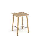 Square wooden table with light oak top, angled wooden legs, and chrome footrest bar, shown against a white background.