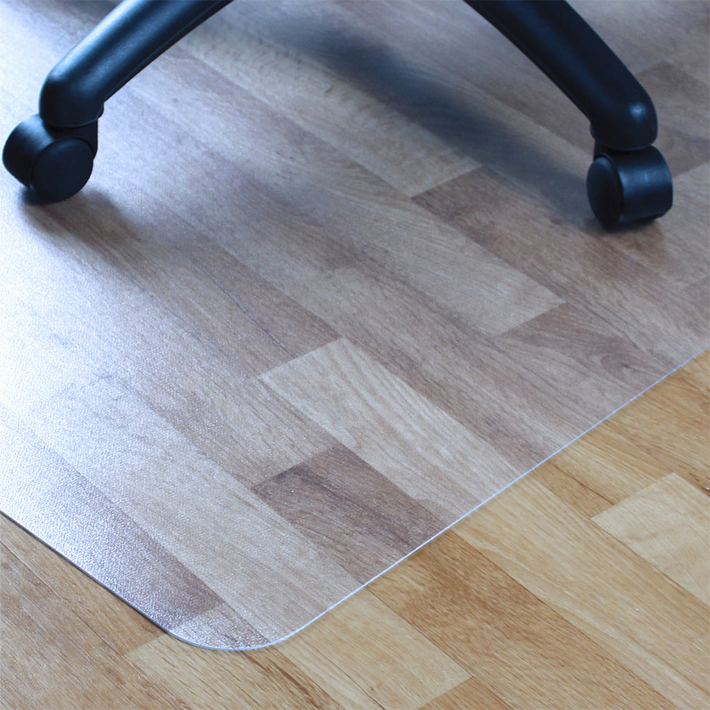Clear office chair floor mat with rounded edges on a wooden floor, showing chair castor wheels for floor protection.