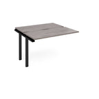 Modular bench desk add-on with a grey wood-effect top, integrated cable access cut-out, and black metal legs, shown on a white background.