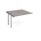 Modular bench desk add-on with a grey wood-effect top, integrated cable access cut-out, and silver metal legs, shown on a white background.