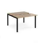 Two-person back-to-back office desk with oak-effect worktops and black metal legs, shown against a white background.