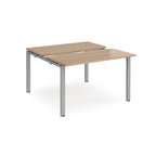 Two-person back-to-back office desk with wood-effect worktops and silver metal legs, shown against a white background.
