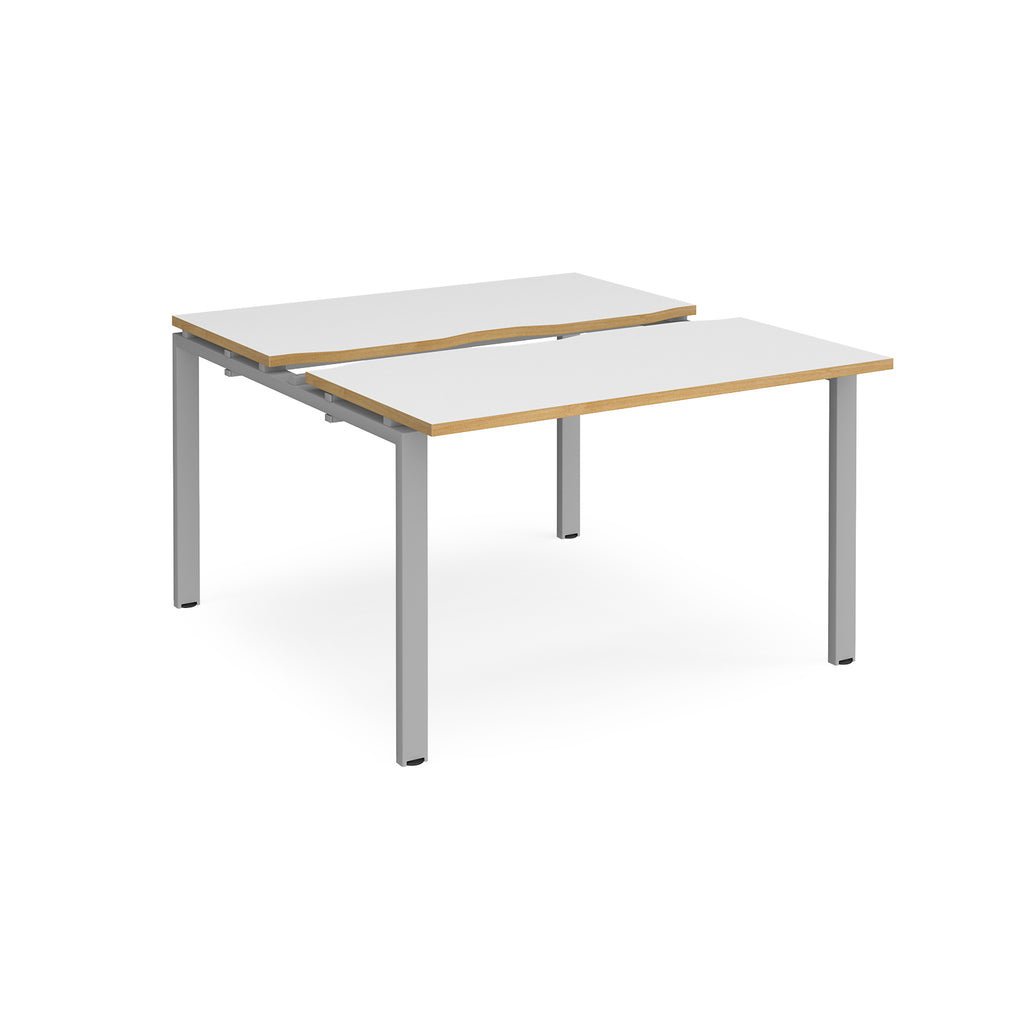 Two-person back-to-back office desk with white worktops, oak-effect edging, and silver metal legs, shown against a white background.