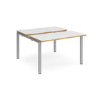 Two-person back-to-back office desk with white worktops, oak-effect edging, and silver metal legs, shown against a white background.