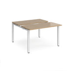 Two-person back-to-back office desk with oak-effect worktops and white metal legs, shown against a white background.