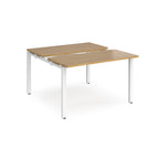 Two-person back-to-back office desk with oak-effect worktops and white metal legs, designed for shared workspace layouts.