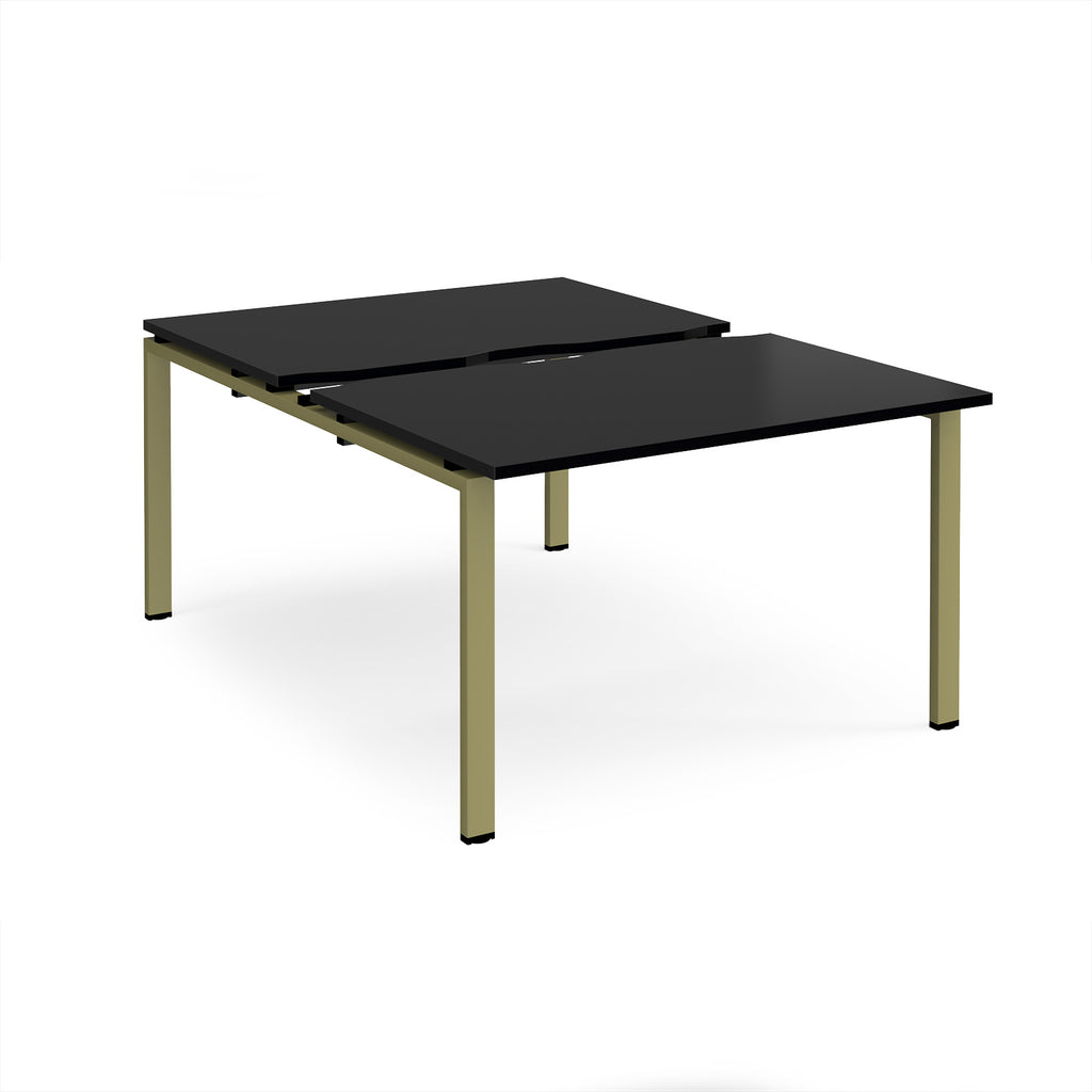 Large modular bench desk with a black worktop, integrated cable access cut-outs, and green metal legs, shown on a white background.