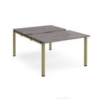 Large modular bench desk with a grey wood-effect top, integrated cable access slots, and green metal legs, shown on a white background.