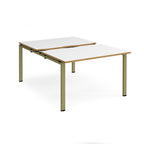 Large modular bench desk with white panels and wood-effect edging, integrated cable access cut-outs, and green metal legs, shown on a white background.