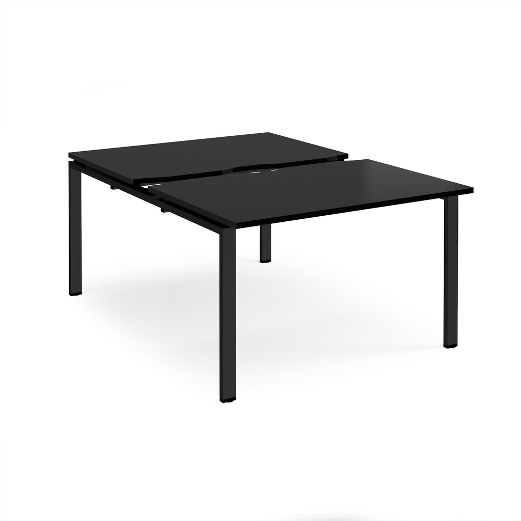 Large modular bench desk with a black top, integrated cable access cut-out, and black metal legs, shown on a white background.