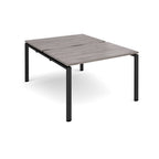 Large modular bench desk with a grey wood-effect top, integrated cable access cut-out, and black metal legs, shown on a white background.
