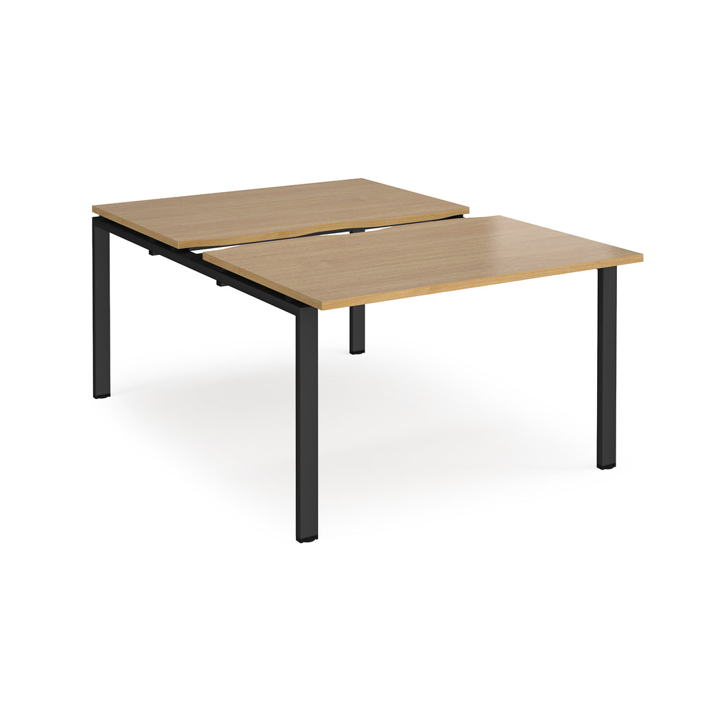 Large modular bench desk with a wood-effect top, integrated cable access cut-out, and black metal legs, shown on a white background.