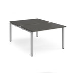 Large modular bench desk with a grey top, integrated cable access cut-out, and silver metal legs, shown on a white background.