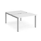 Large modular bench desk with a white top, integrated cable access cut-out, and silver metal legs, shown on a white background.