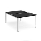 Large modular bench desk with a black worktop, integrated cable access cut-outs, and white metal legs, shown on a white background.