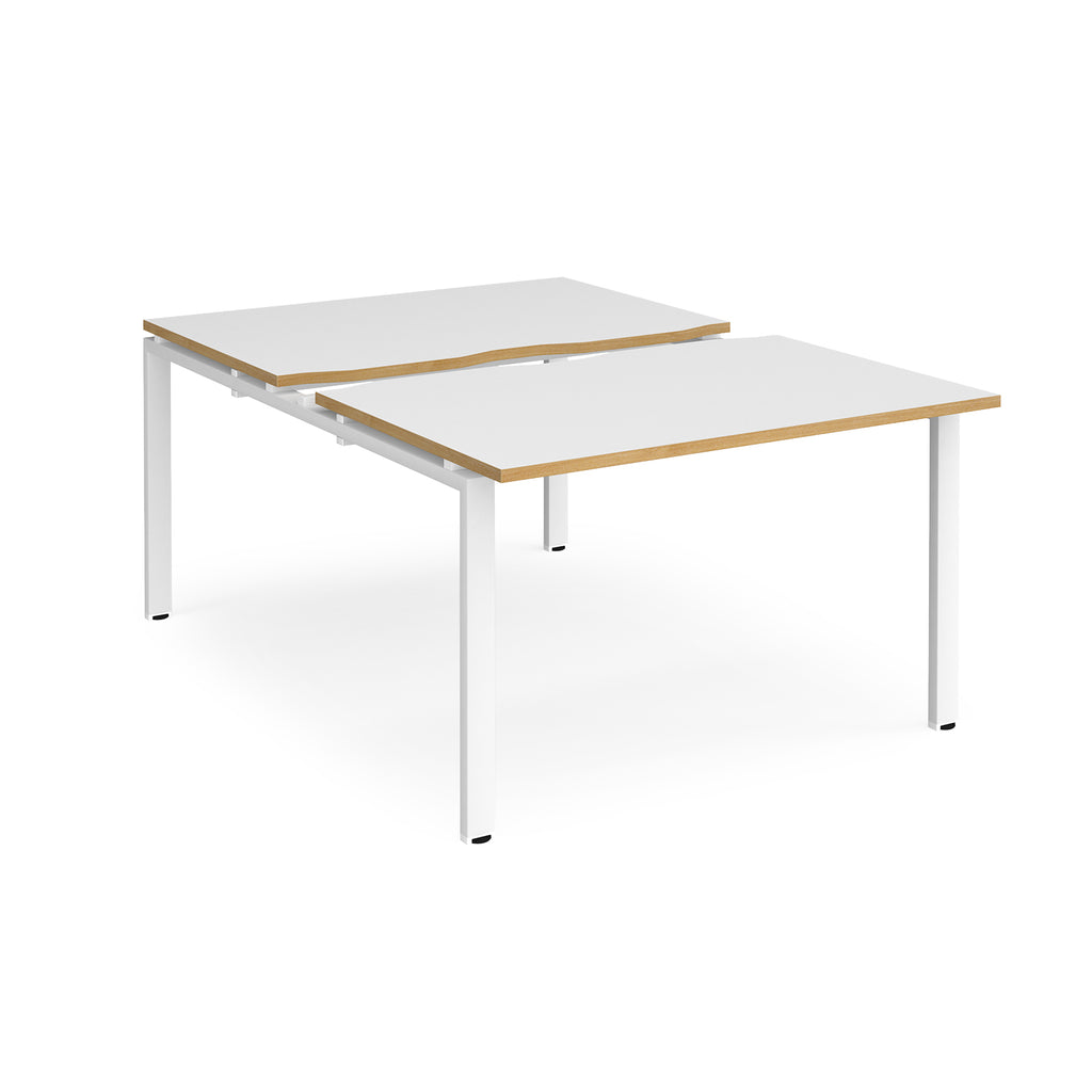 Large modular bench desk with white panels and wood-effect edging, integrated cable access cut-outs, and white metal legs, shown on a white background.