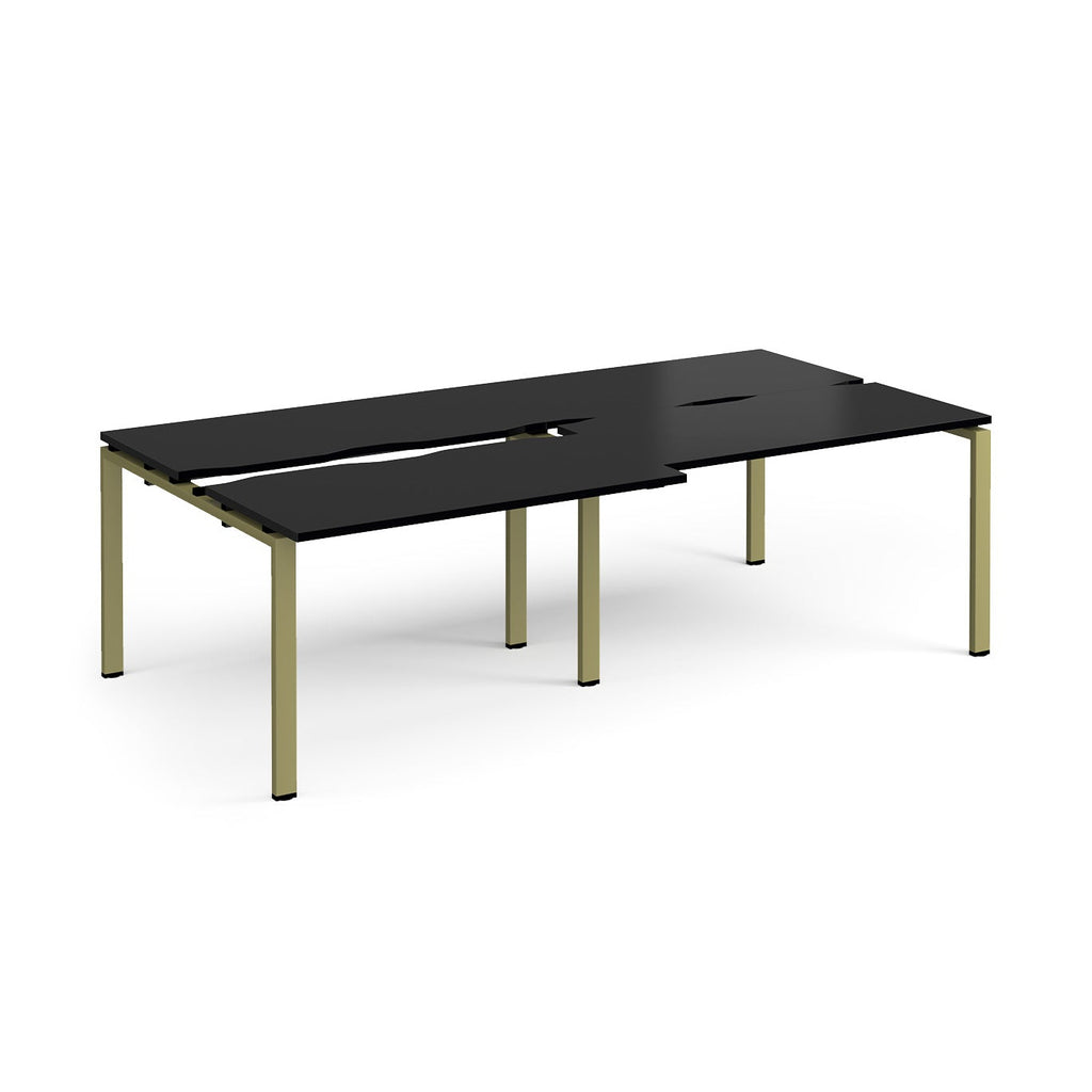 Large modular bench desk with a black worktop, integrated cable access cut-outs, and green metal legs, shown on a white background.
