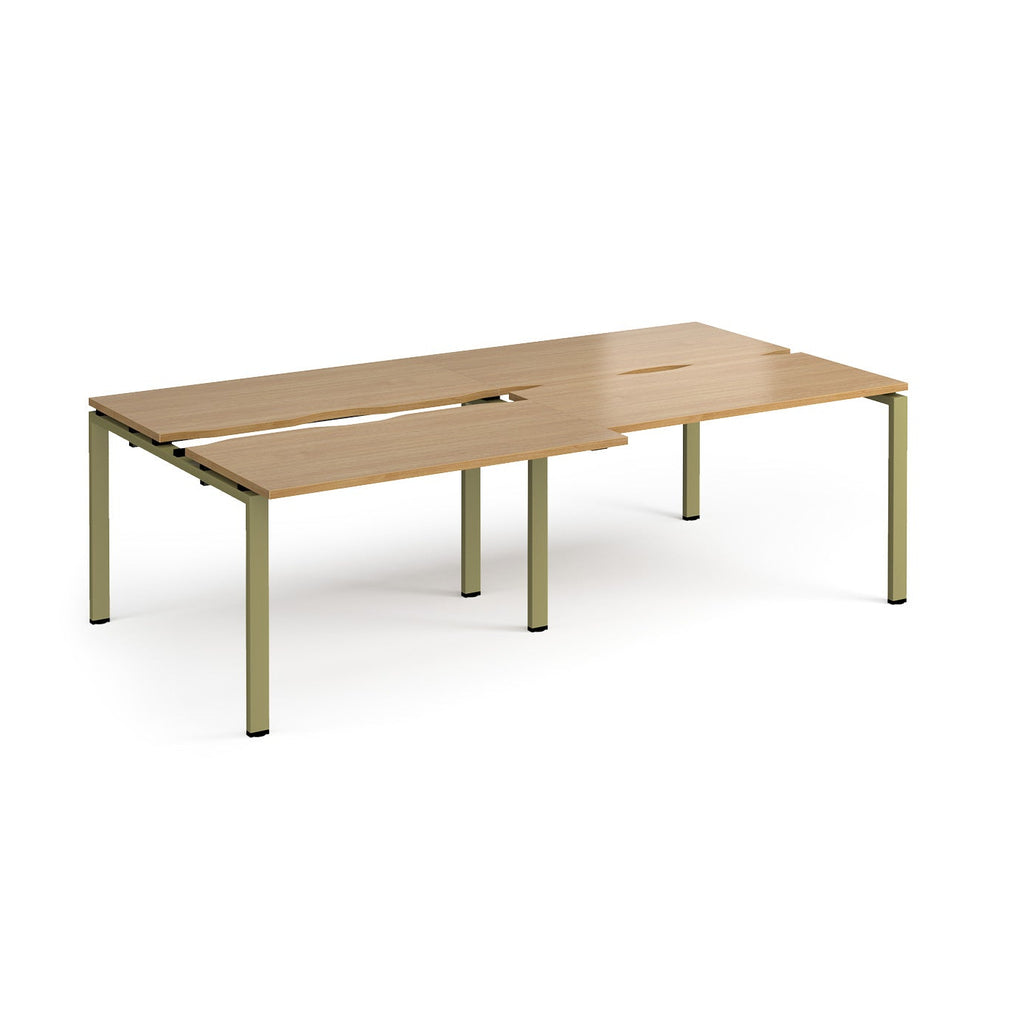 Large modular bench desk with a wood-effect top, integrated cable access cut-outs, and green metal legs, shown on a white background.