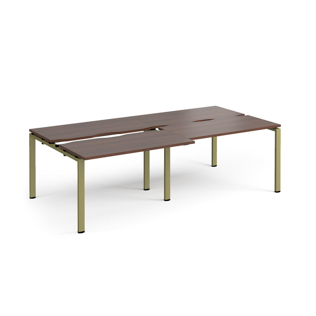 Large modular bench desk with a dark wood-effect top, integrated cable access cut-outs, and green metal legs, shown on a white background.