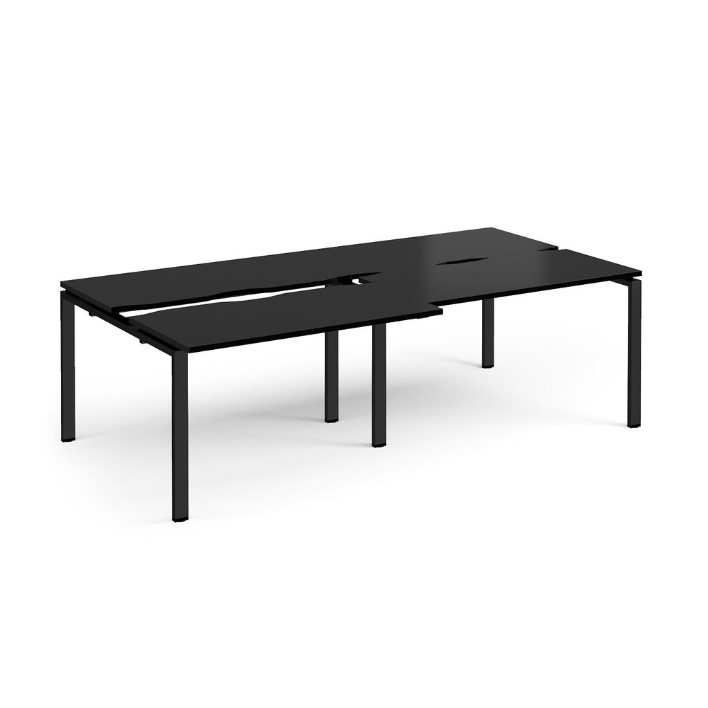 Large modular bench desk with a black worktop, integrated cable access cut-outs, and matching black metal legs, shown on a white background.