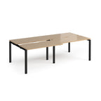 Large modular bench desk with a light oak wood-effect top, integrated cable access cut-outs, and black metal legs, shown on a white background.