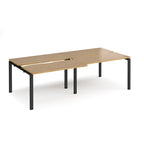 Large modular bench desk with a light oak wood-effect top, integrated cable access cut-outs, and black metal legs, shown on a white background.