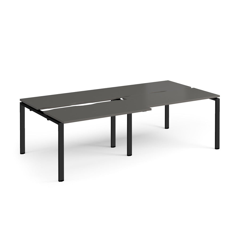 Large modular bench desk with a grey worktop, integrated cable access cut-outs, and black metal legs, shown on a white background.