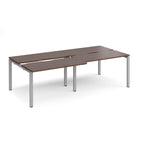 Large modular bench desk with a dark wood-effect top, integrated cable access cut-outs, and silver metal legs, shown on a white background.