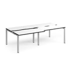 Large modular bench desk with a white worktop, contrasting black edge detail, integrated cable access cut-outs, and silver metal legs, shown on a white background.
