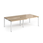 Large modular bench desk with a light wood-effect top, integrated cable access cut-outs, and white metal legs, shown on a white background.