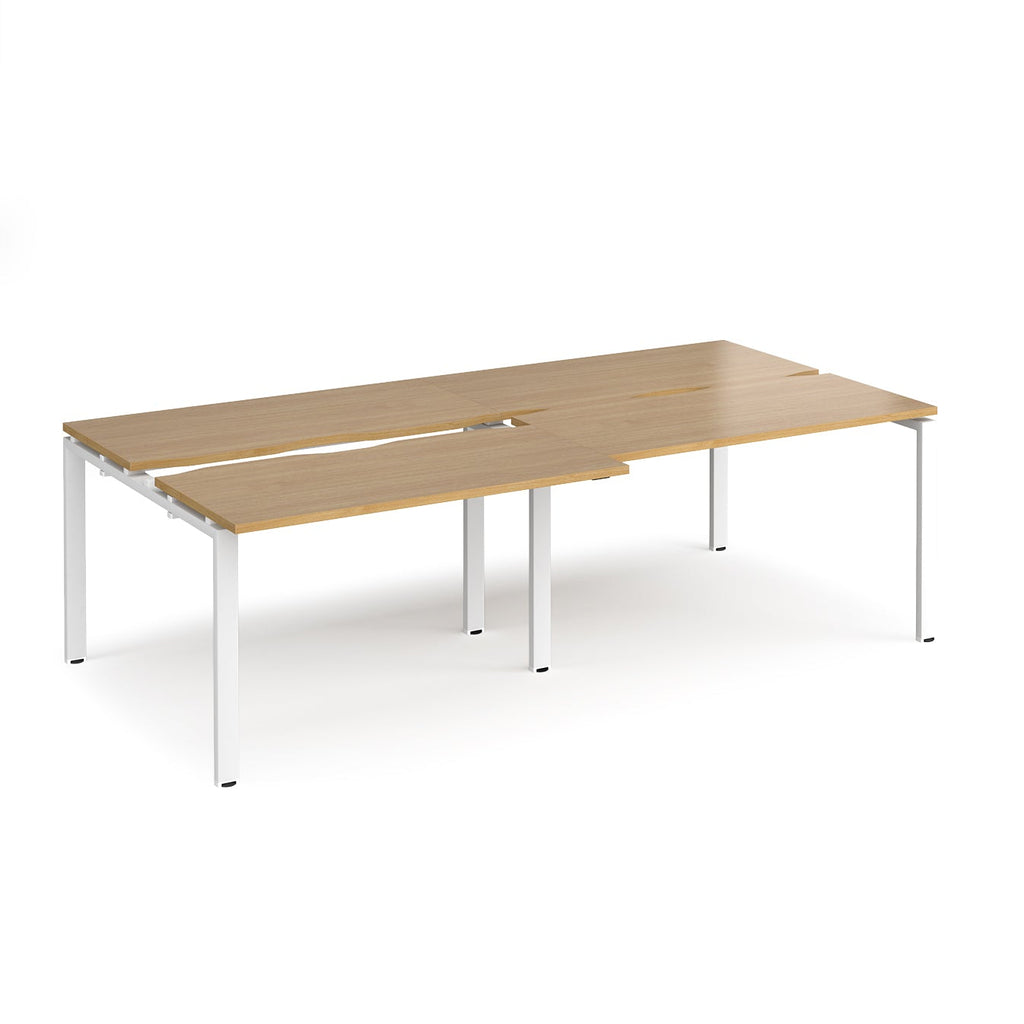 Large modular bench desk with a oak wood-effect top, integrated cable access cut-outs, and white metal legs, shown on a white background.