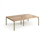 Large modular bench desk with a light wood-effect top, integrated cable access cut-outs, and green metal legs, shown on a white background.