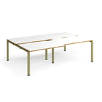 Large modular bench desk with white panels and wood-effect edging, integrated cable access cut-outs, and green metal legs, shown on a white background.
